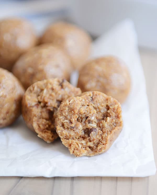 A parchment sheet with protein balls on top. The front two balls have bites taken out of them. 