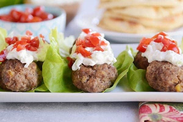 Three lettuce wraps filled with falafel meatballs, tzatziki sauce, and chopped peppers.