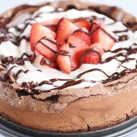 Fallen chocolate cake with whipped cream, strawberries, and chocolate drizzle.