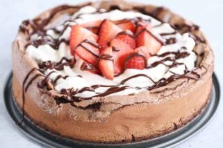 Fallen chocolate cake with whipped cream, strawberries, and chocolate drizzle.