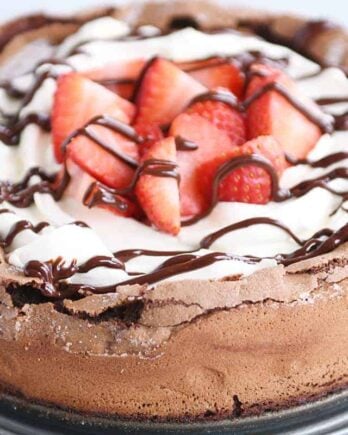 Fallen chocolate cake with whipped cream, strawberries, and chocolate drizzle.