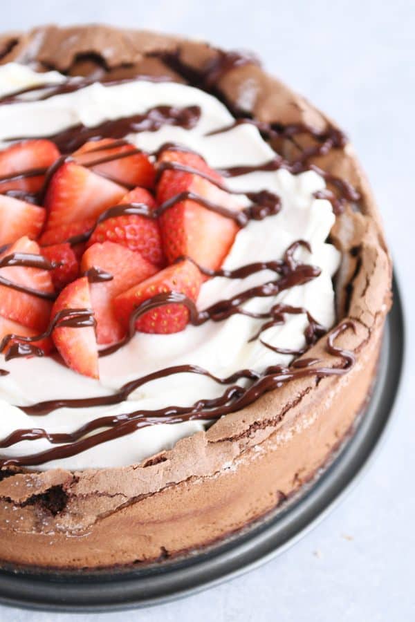 Fallen chocolate cake with whipped cream, strawberries, and chocolate drizzle.