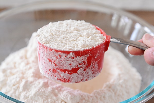 Side view of a red measuring cup full of flour. 