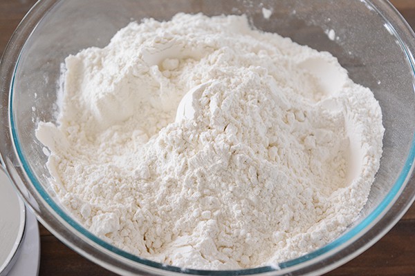 A clear bowl full of white flour.