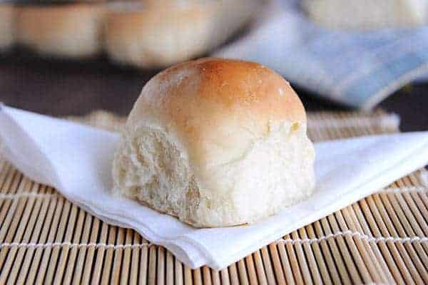 a cooked, french bread roll sitting on a white napkin and bamboo mat. 