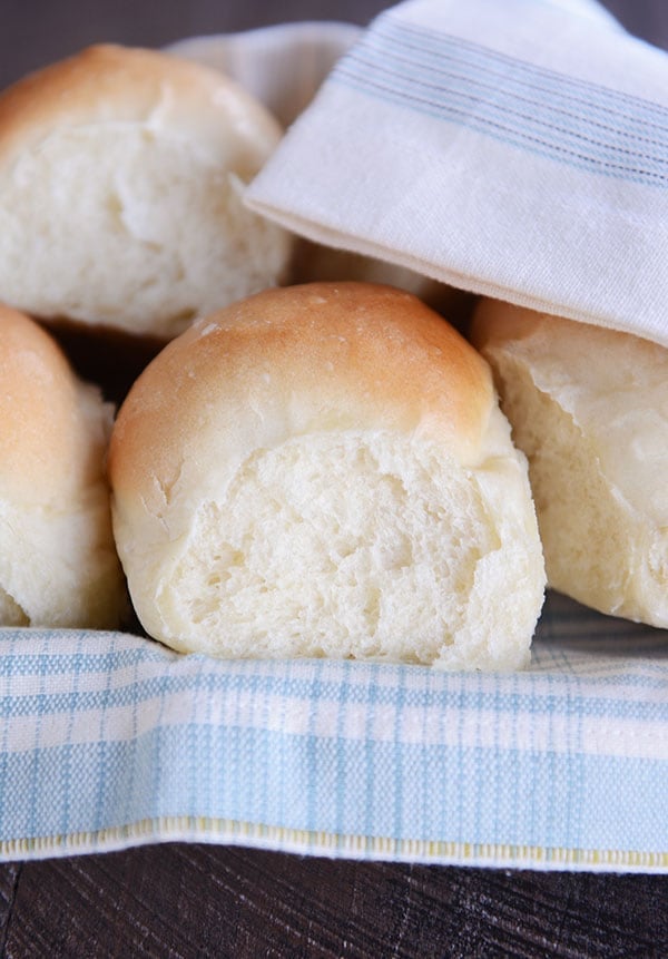 French bread rolls on a white and blue napkin inside a basket. 