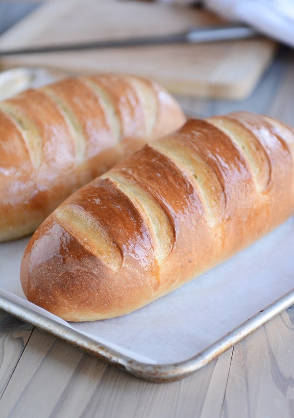 Two loaves of fresh homemade French Bread on a parchment-lined sheet pan.