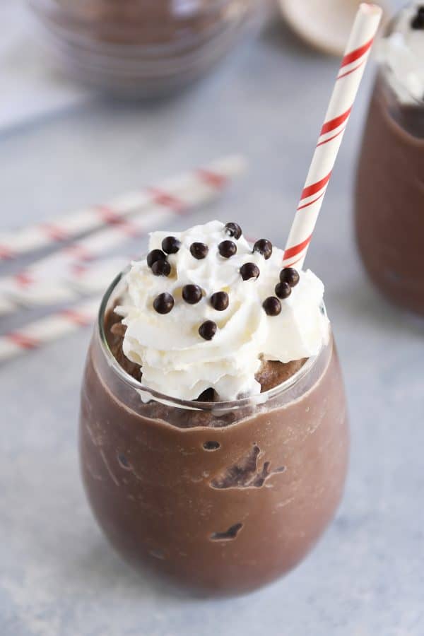 Frozen hot chocolate in clear glass with whipped cream and straw.