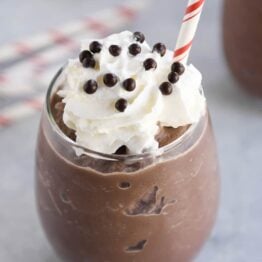 Frozen hot chocolate in clear glass with whipped cream and straw.