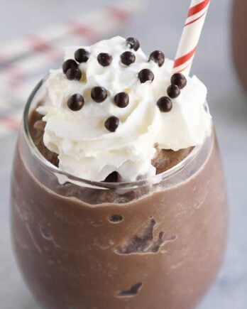 Frozen hot chocolate in clear glass with whipped cream and straw.