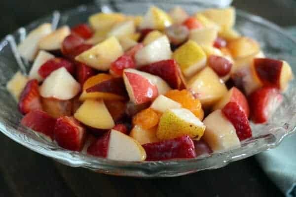 Clear glass bowl of fruit salad with a light glaze. 