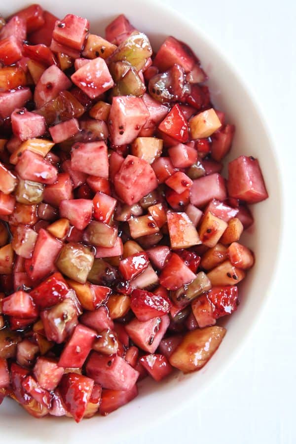 Top down view of white shallow bowl with mixed fruit salsa.