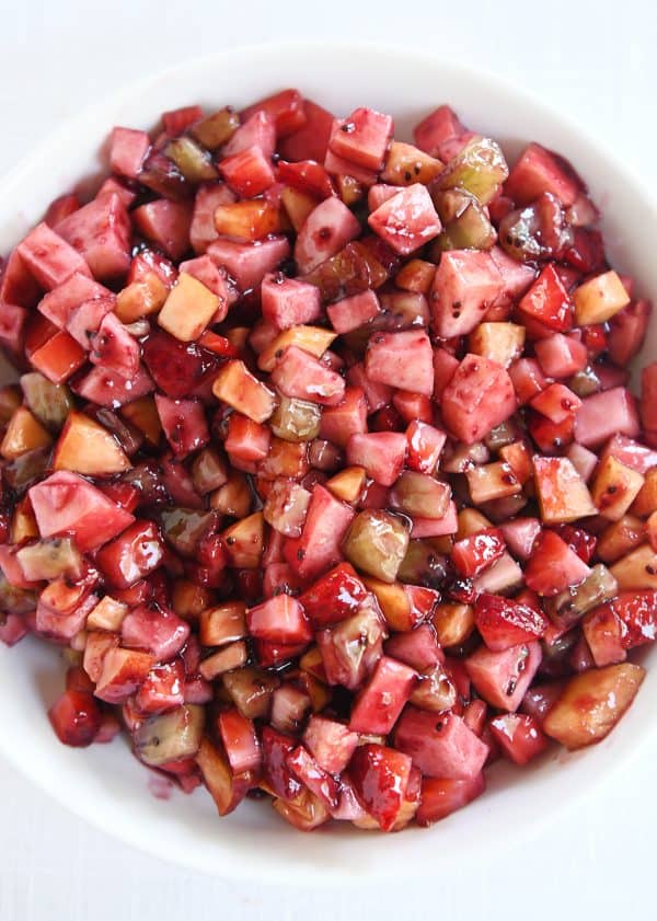 Top down view of white shallow bowl with mixed fruit salsa.