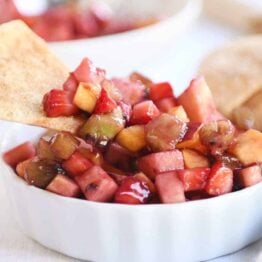 Small white bowl with fruit salsa with baked cinnamon tortilla chips.