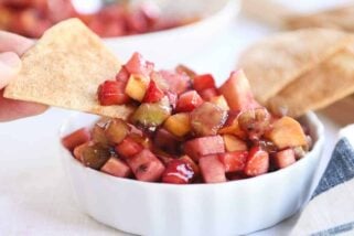 Small white bowl with fruit salsa with baked cinnamon tortilla chips.