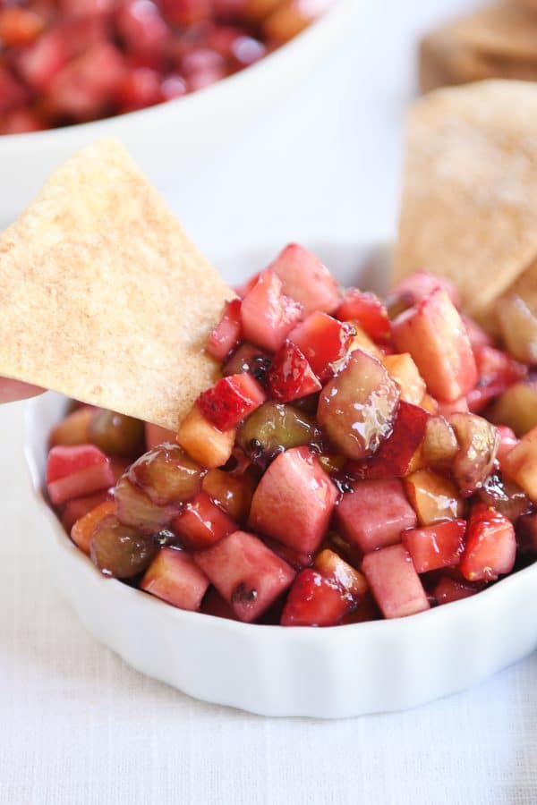 Small white bowl with fruit salsa with baked cinnamon tortilla chips.