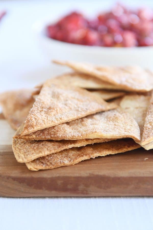 Baked cinnamon tortilla chips on wood cutting board.