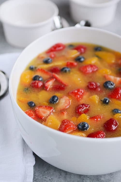 A large white bowl full of berry and mandarin orange fruit soup. 