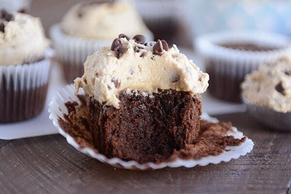 A chocolate cupcake with a thick layer of frosting and a bite taken out.