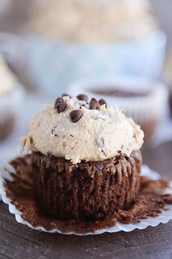 An unwrapped chocolate cupcake with a thick layer of cookie dough frosting on top.