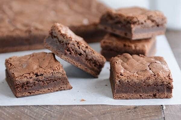 Five cut up brownies in front of the rest of the slab of brownie.