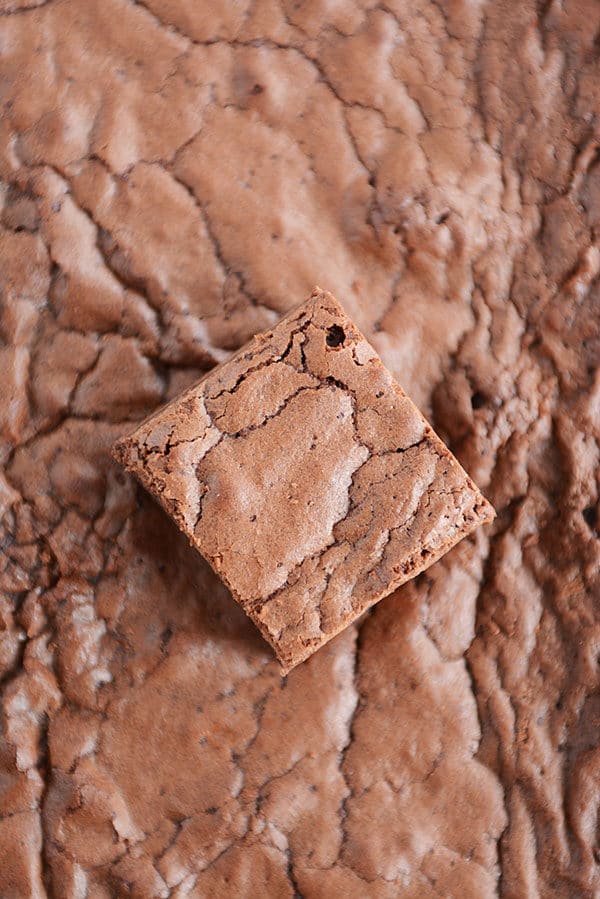 A cut up brownie on top of a pan of brownies.