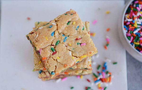 sprinkle-filled blondie bars stacked on each other on a piece of parchment