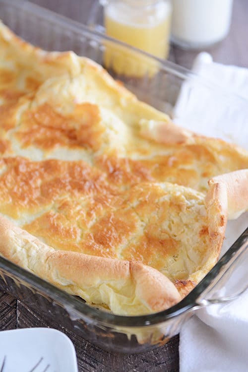 A glass 9x13 pan with a golden-topped baked german pancake inside. 