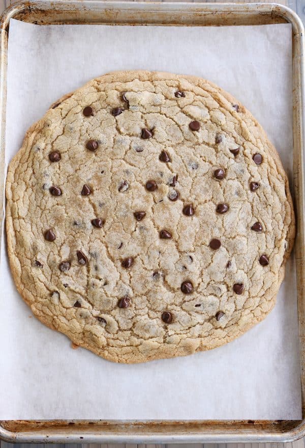 Giant chocolate chip cookie baked on a sheet pan.