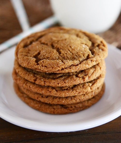 A stack of five brown molasses cookies on a white plate. 