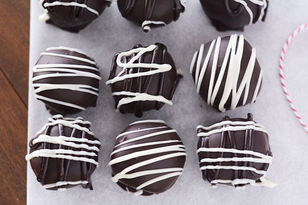 Top view of white chocolate drizzled chocolate gingerbread truffles on a piece of parchment.