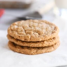 Three gingerbread oatmeal cookies stacked on white napkin.