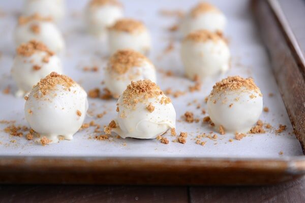 White chocolate truffles with crushed graham cracker on top on a cookie sheet.