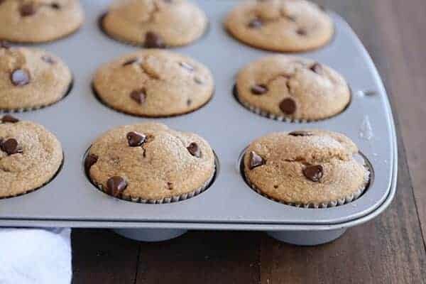 A muffin tin full of cooked chocolate chip banana muffins. 