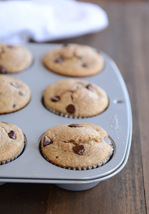 Cooked chocolate chip banana muffins in a metal muffin tin. 