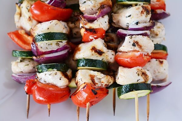 Top view of a stack of Greek chicken and vegetable kebabs. 