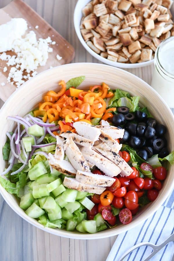 Top down view of chopped Greek salad in white bowl without dressing.