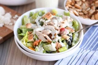 White bowl of chopped Greek chicken salad with tzatziki dressing.