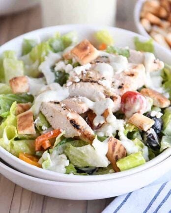 White bowl of chopped Greek chicken salad with tzatziki dressing.