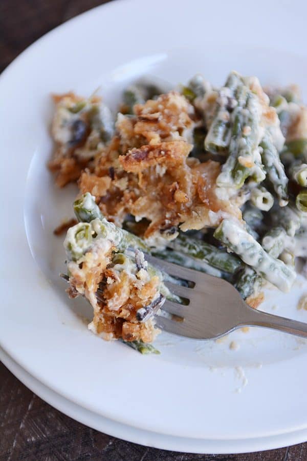 A large helping of green bean casserole topped with crunchy topping on a white plate.