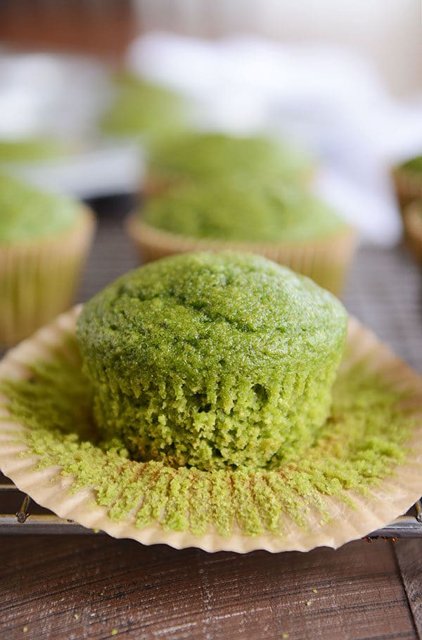 A green muffin on a cooling rack with the liner peeled off.