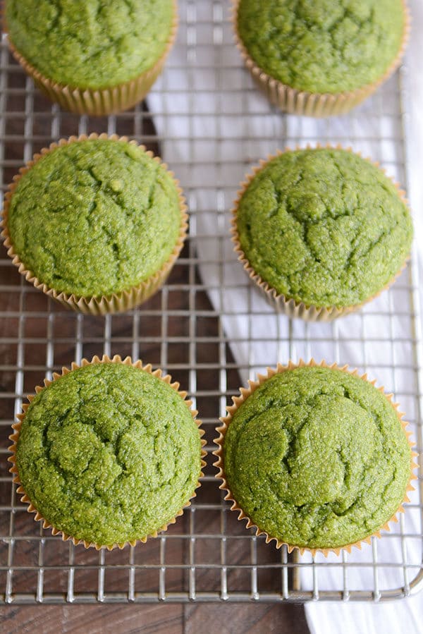 Top down view of six green muffins on cooling rack. 