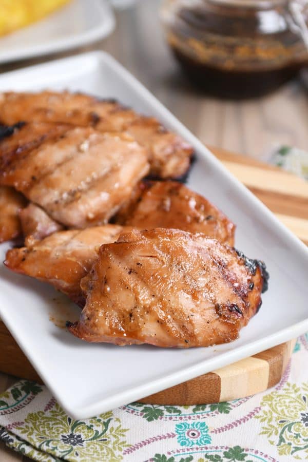 Grilled hawaiian chicken thighs on white platter.