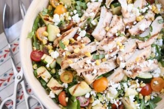 Top down view of grilled chicken orzo salad in white serving bowl.