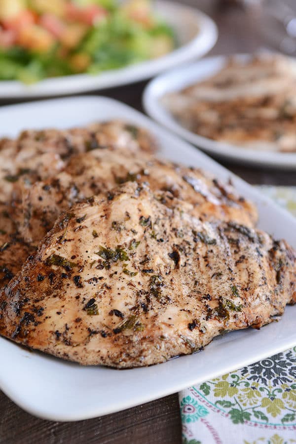 A white platter of grilled chicken breasts.