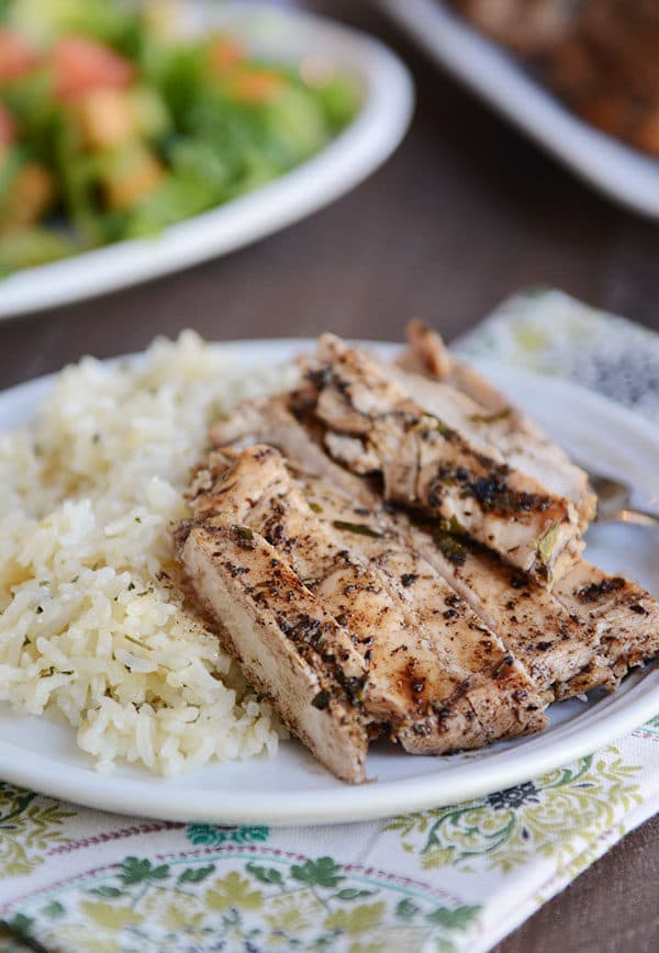 A white plate of cooked rice and sliced grilled chicken breast.