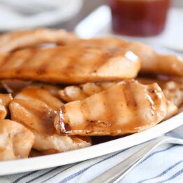 White platter of grilled sweet and sour chicken pieces.