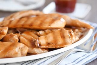 White platter of grilled sweet and sour chicken pieces.