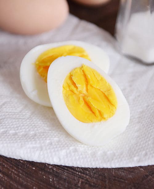 A hard boiled egg that has been cut in half sitting on a napkin.