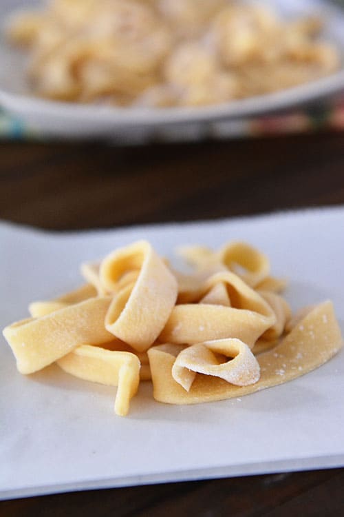 Uncooked, fresh egg noodles on a piece of parchment paper. 